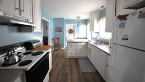 A kitchen with white cabinets, a stove, and a refrigerator. There is a wooden chair and a rug on the floor. - Walking distance to shopping, restaurants, entertainment, and the Chesapeake Bay (Rock Hall)