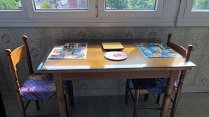 Una mesa de comedor con cubierta de vidrio, rodeada por sillas de madera con tapicería floral.