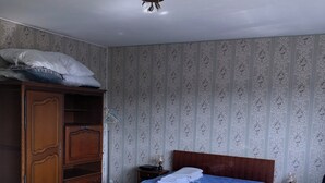 Un dormitorio con cama y escritorio de madera, un armario y una lámpara en el techo.
