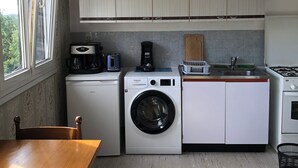 Una cocina compacta con lavadora, cafetera y estufa.