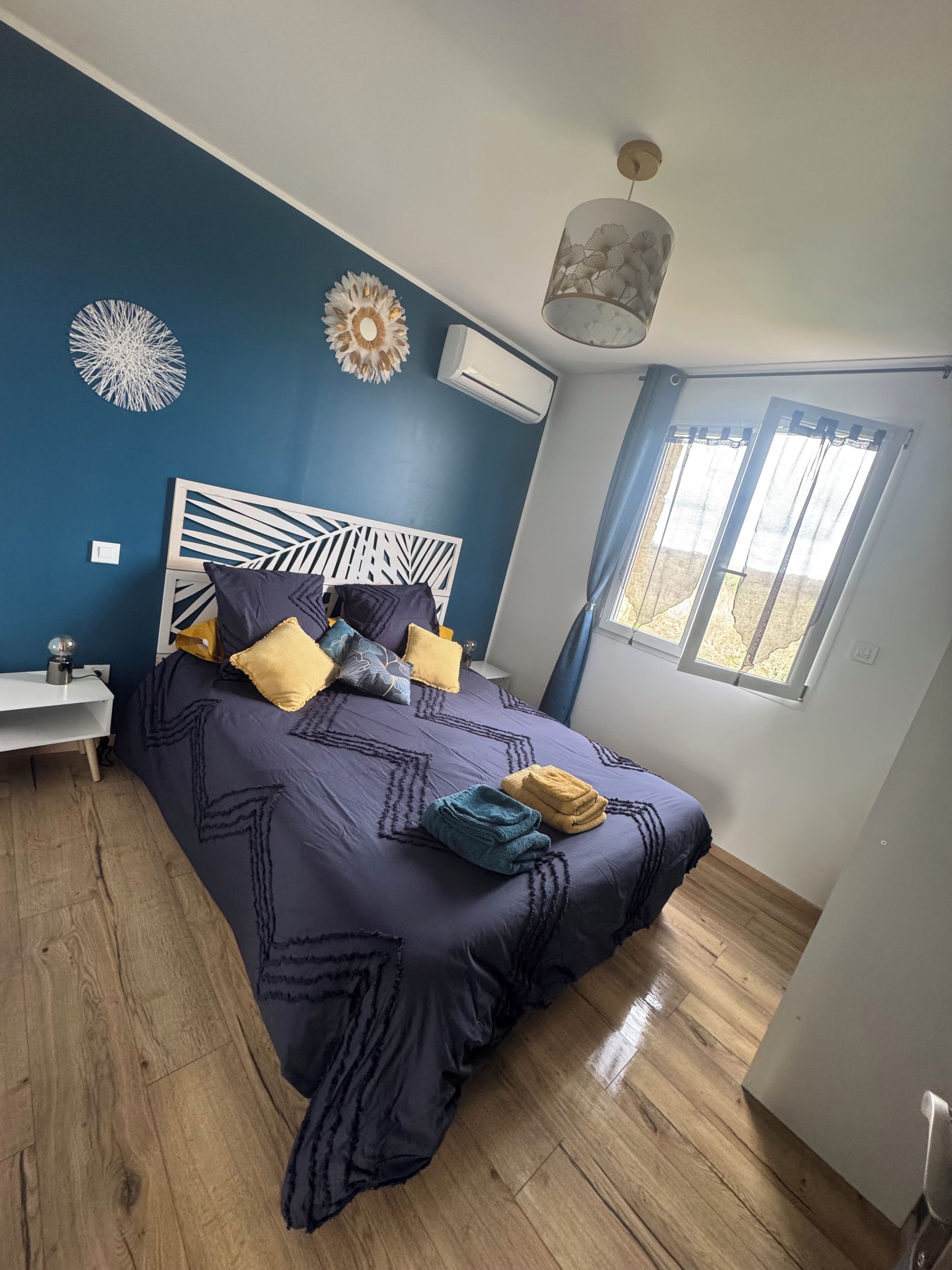 Une chambre à coucher avec un lit, une table de chevet et une fenêtre avec des rideaux.