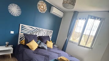 Une chambre à coucher avec un lit, une table de chevet et une fenêtre avec des rideaux.