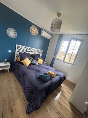 Een slaapkamer met een bed, nachtkastje en een raam met gordijnen.