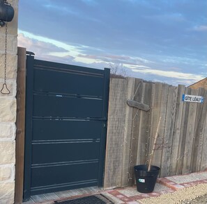 Une porte noire, une clôture en bois et une enseigne sur laquelle on peut lire : « GÎTE LÉALY ».