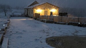 A snow-covered path leading to a stone building with a wooden fence.