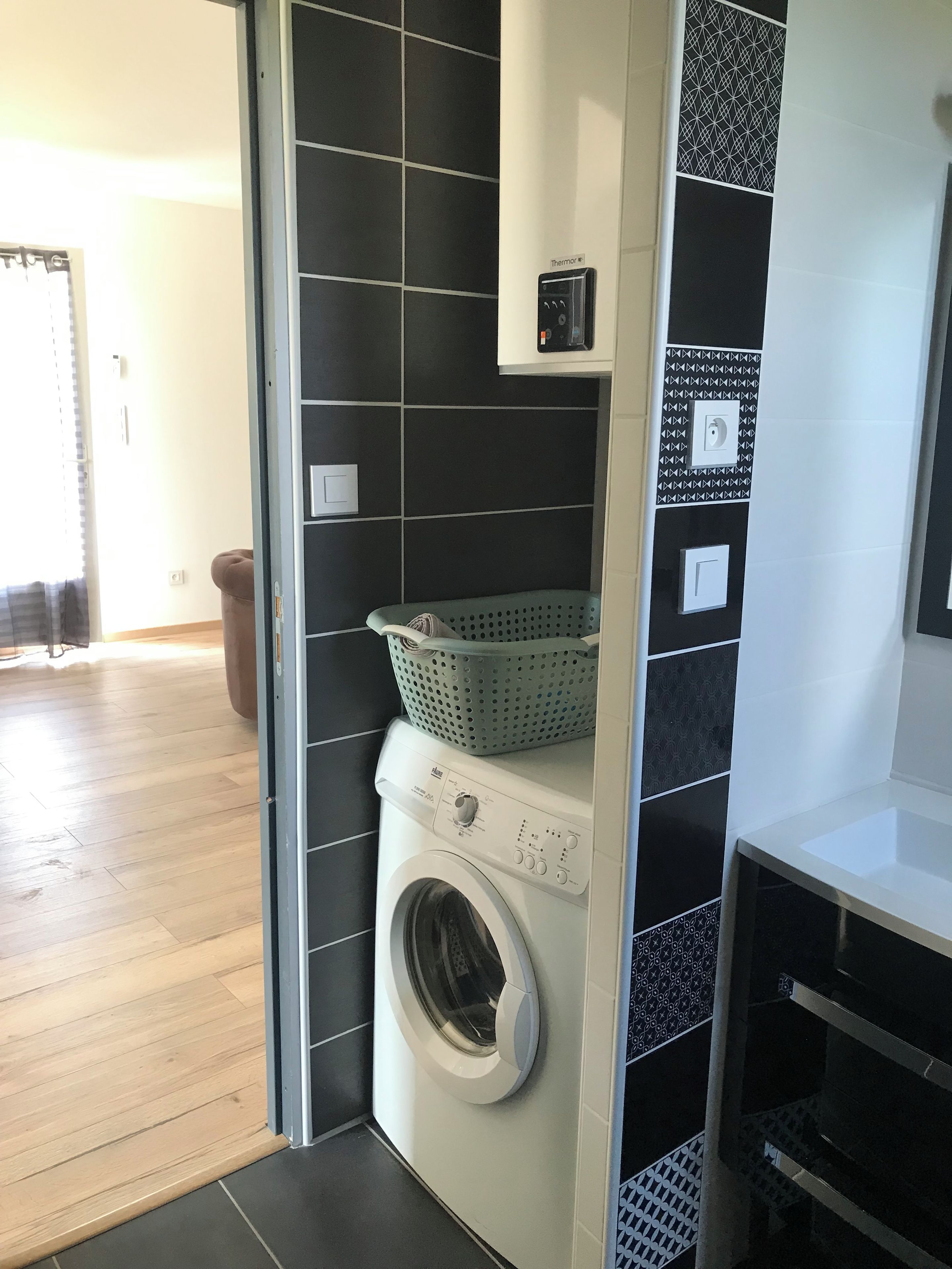 A laundry room with a washing machine, a drying rack, and a basket.