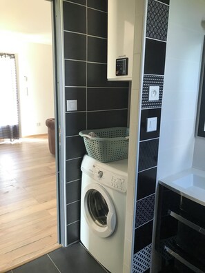 A laundry room with a washing machine, a drying rack, and a basket.