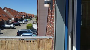 Una strada residenziale con auto parcheggiate e case.