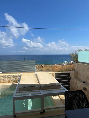 A pool area with a view of the ocean, a lounge chair, and a table. - MyPanormo Suites - Philip (Panormo)
