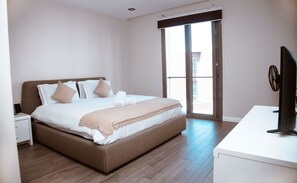Une chambre à coucher avec un lit, une table de chevet, un bureau et un téléviseur.