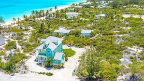 An aerial view of a coastal property with multiple buildings, a beach, and a clear view of the ocean. - Colorful Beach Home w/ Ocean Front View + 2 Master Bedrooms (Exuma)