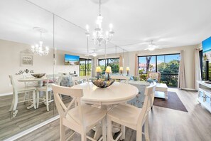 A modern dining area with a round table, white chairs, and a chandelier.