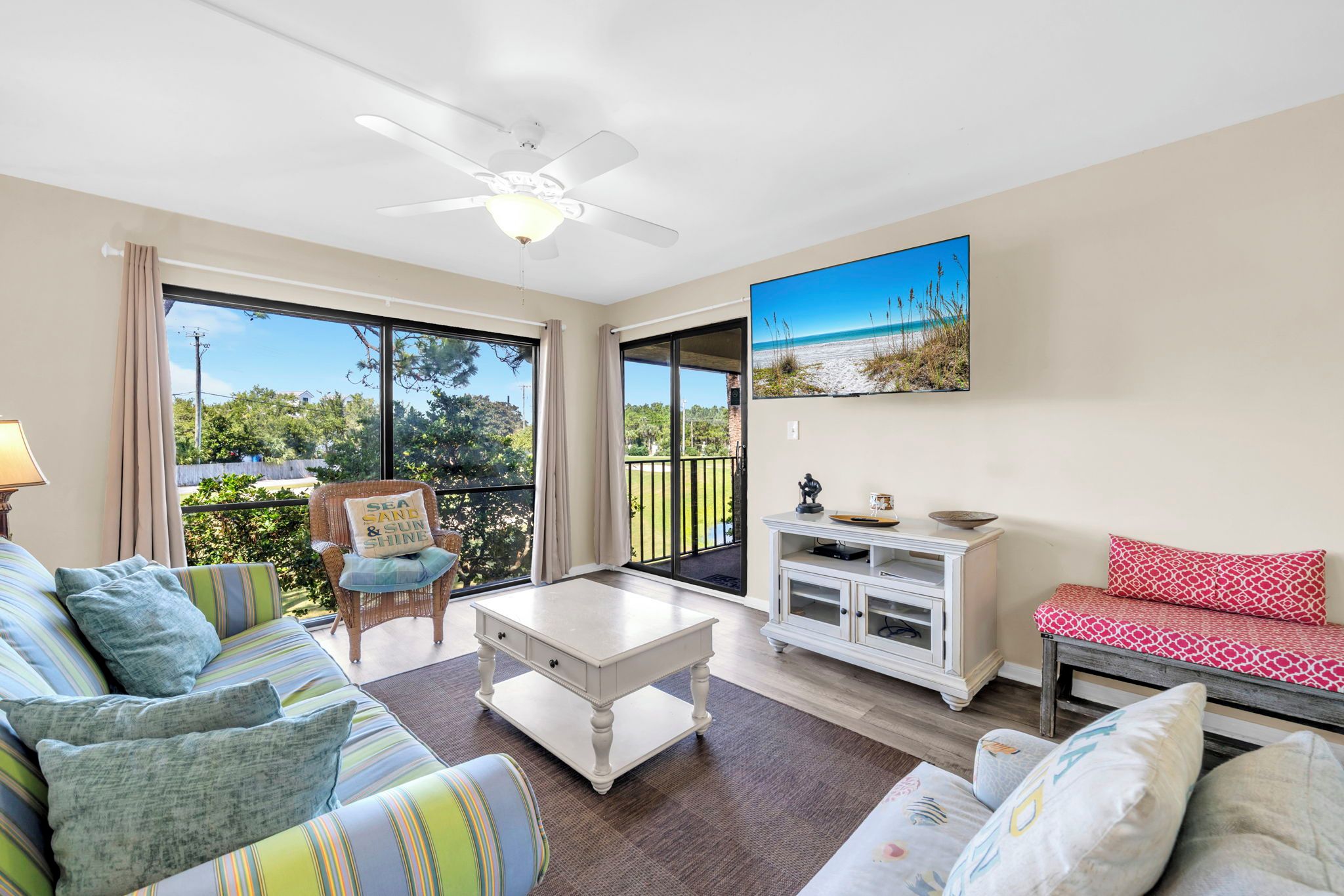 A spacious living room with a sofa, a coffee table, a chair, and a TV mounted on the wall.