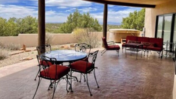 Patio esterno con tavolo rotondo e sedie, un divano rosso e vista sul paesaggio circostante.