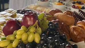 Une table garnie d’une variété d’aliments, notamment des raisins, du pain et des pots de confitures.