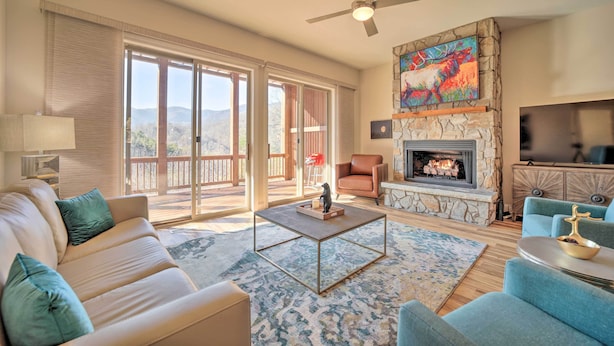 A spacious living room with a beige sofa, a coffee table, and a fireplace. - Beautiful Whittier Condo w/ Deck + Mtn Views! (Whittier)