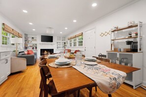 Una cocina moderna con comedor, suelo de madera y electrodomésticos empotrados.