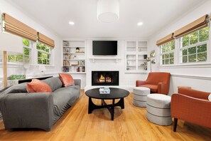 A modern living room with a fireplace, a sofa, a coffee table, and a television.