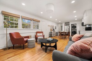 A modern living room with a sofa, armchairs, a coffee table, and a dining area with chairs. - Elon Dream Home: Spacious Retreat w/ Private Game Room (Gibsonville)