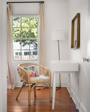 A room with a wicker chair, a white desk, a lamp, and a window with curtains. - Elon Dream Home: Spacious Retreat w/ Private Game Room (Gibsonville)