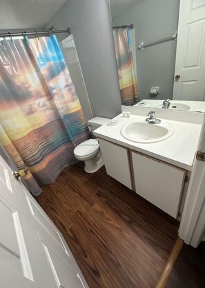 Un bagno con un lavandino bianco, un water e una tenda da doccia con un motivo colorato.