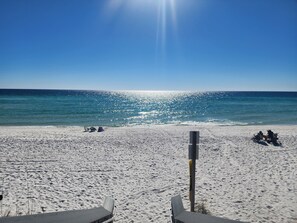 A beach with a clear view of the ocean, a sandy shore, and a few beach chairs and umbrellas.