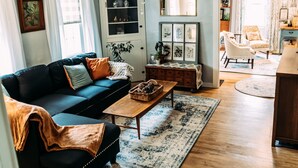 Un salon chaleureux avec un canapé bleu foncé, une table basse en bois et un tapis à motifs.