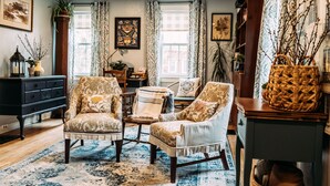 Un salon chaleureux avec des fauteuils à motifs, une table basse et une bibliothèque.