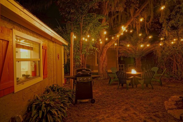 Eine gemütliche Terrasse im Freien mit Lichterketten, einem Grill und Sitzgelegenheiten.