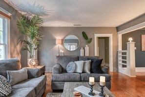 Ein Wohnzimmer mit grauem Sofa, einem Couchtisch mit Kerzen und einer großen Topfpflanze.