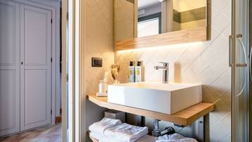 Une salle de bain moderne avec un grand lavabo blanc, un miroir et une douche.