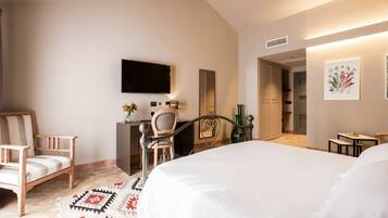 A hotel room with a bed, a desk, a chair, a television, and artwork on the walls.