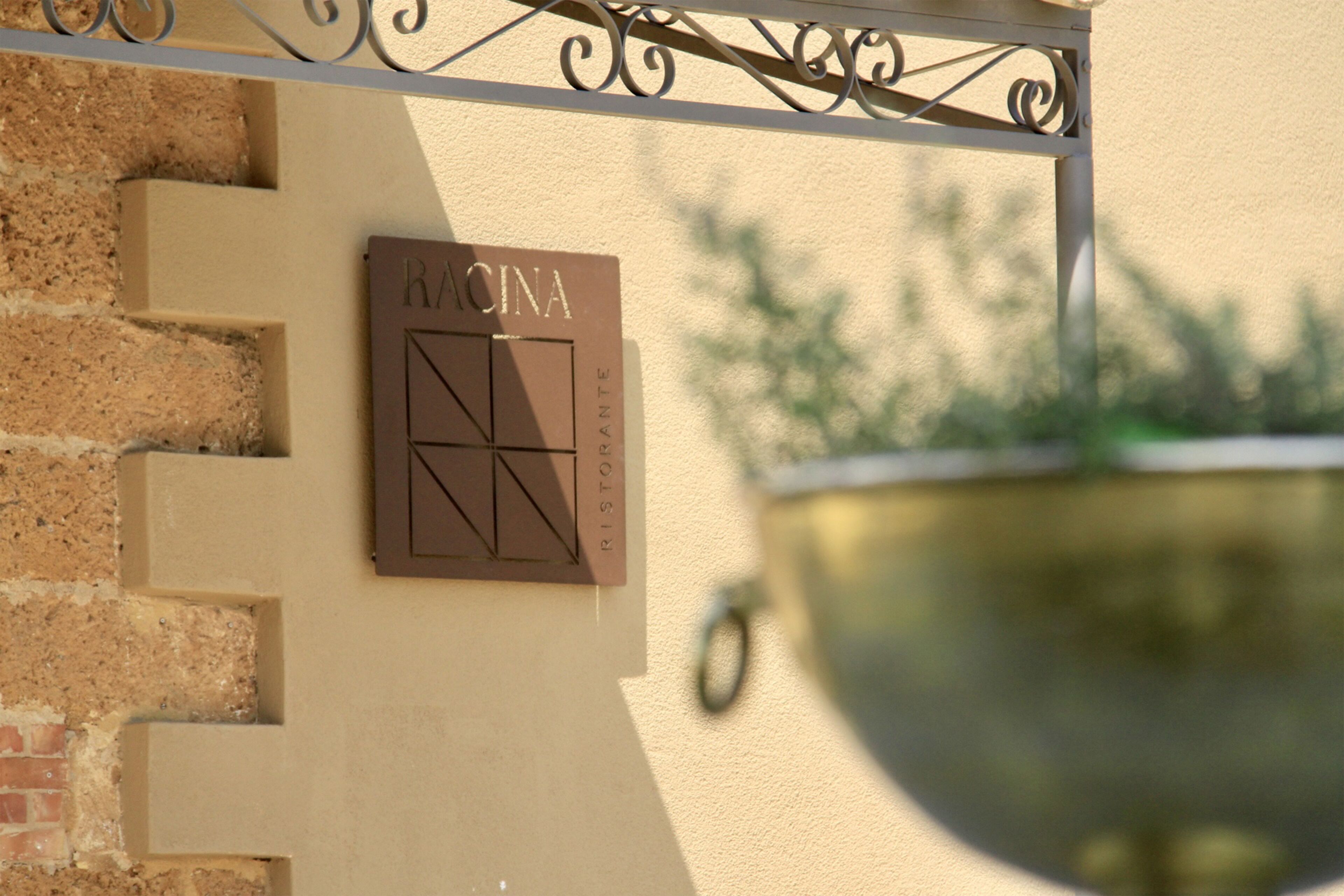 A wall-mounted sign with the name "RACINA" and a geometric design.