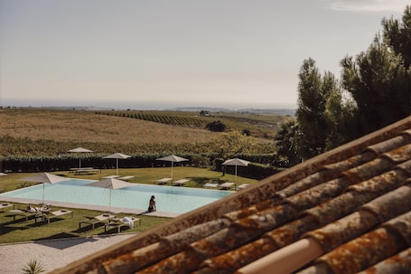 Una piscina al aire libre, sombrillas, sillones reclinables de piscina. MASSERIA DEL CARBOJ