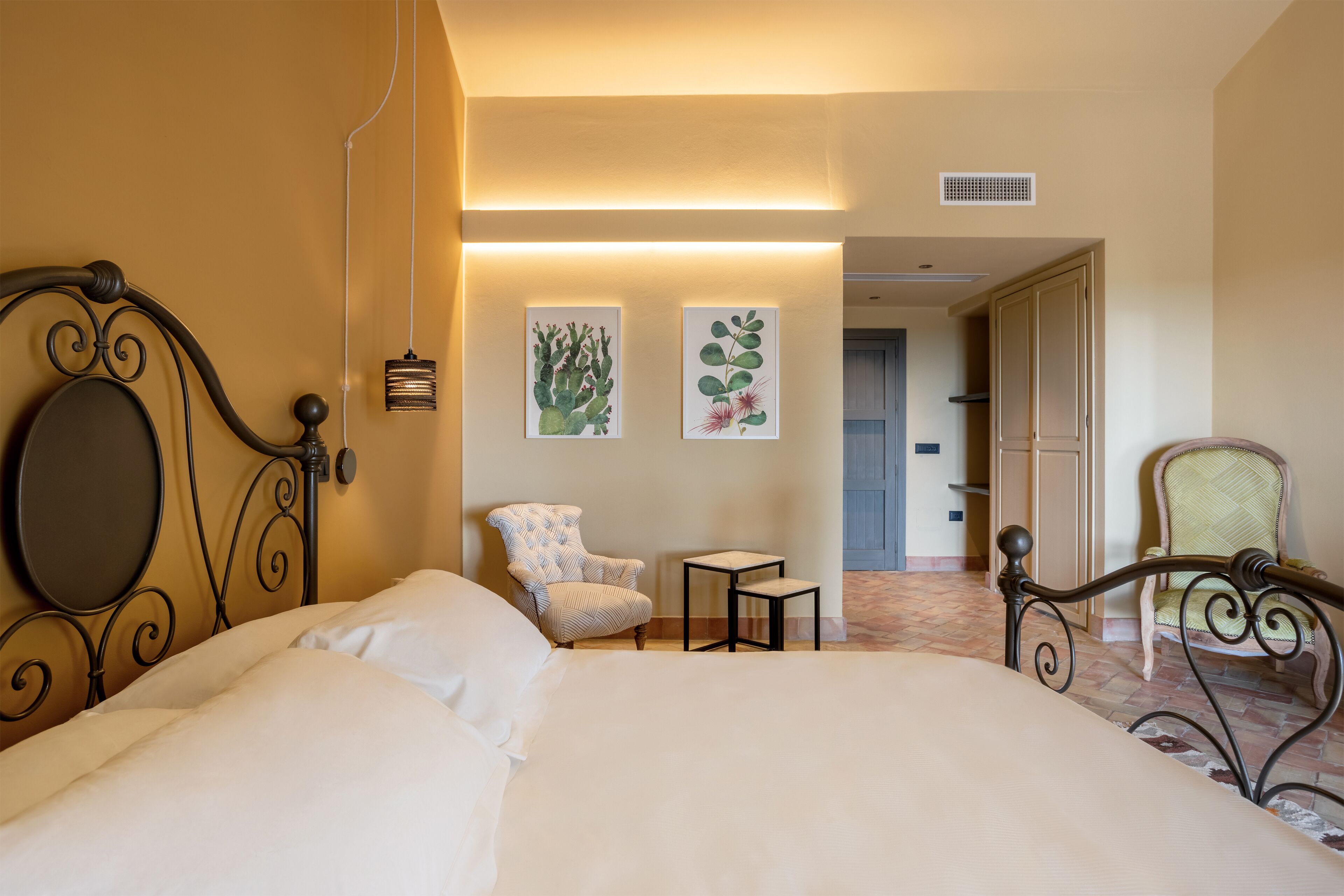A hotel room with a large bed, two chairs, a small table, and wall-mounted artwork.