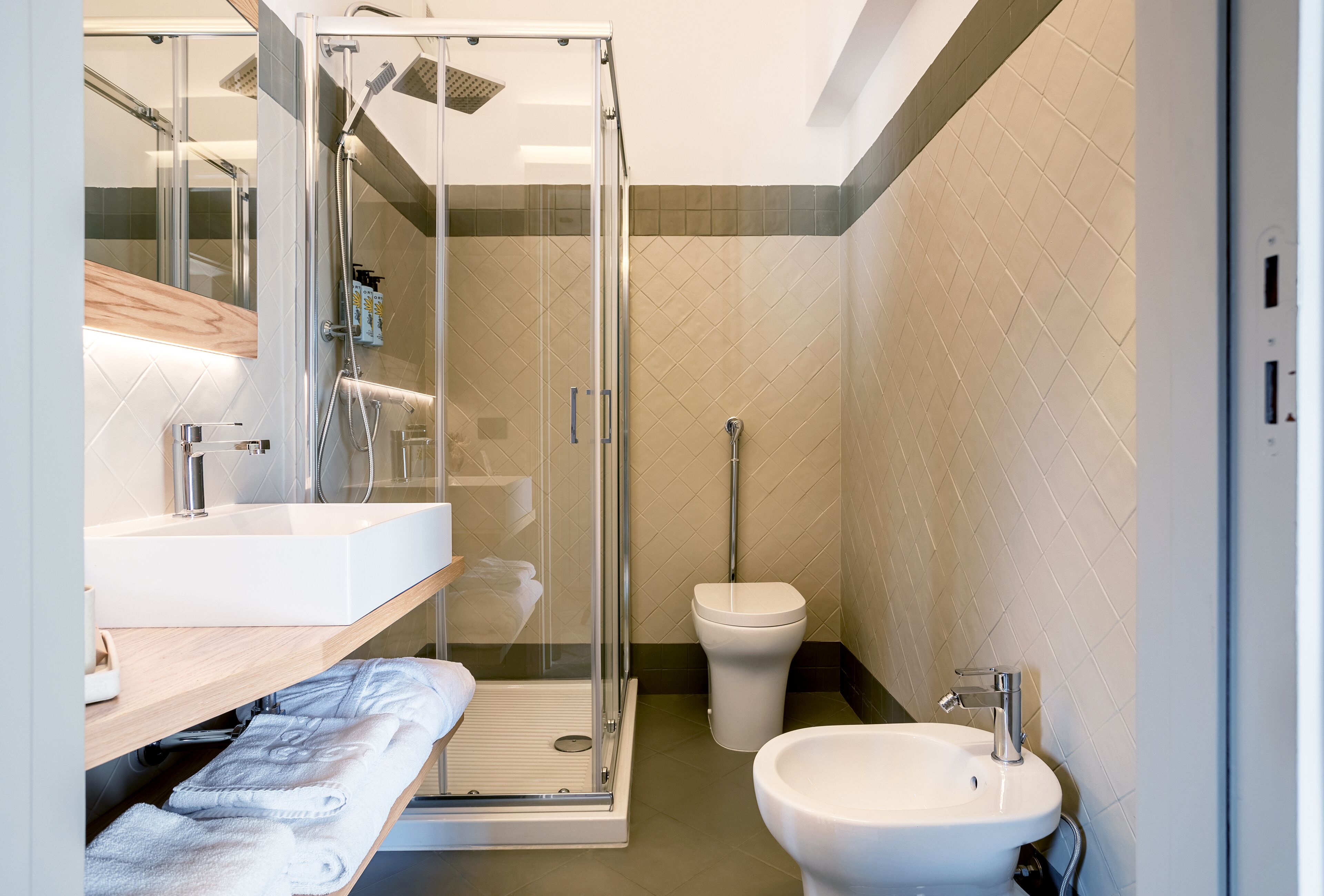 Une salle de bain moderne avec une douche à parois de verre, un lavabo blanc et des toilettes.