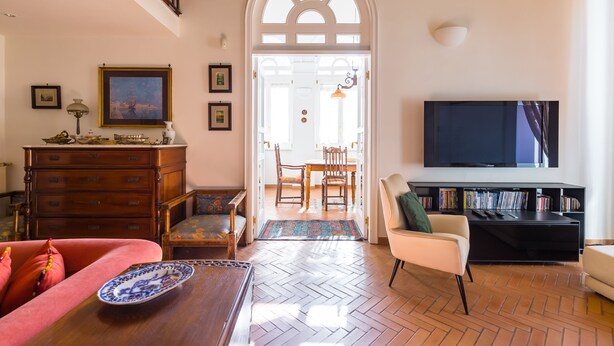 Un salon doté d’un parquet en chevrons, d’un téléviseur, d’une bibliothèque et d’un coin repas avec une table et des chaises.