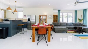 Un espace de vie moderne comprenant un coin repas, une cuisine et un canapé gris.