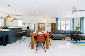 A modern living space with a dining area, kitchen, and a grey sofa. - Incredible 4BR w/ Private Pool near Palm Beach (Noord)