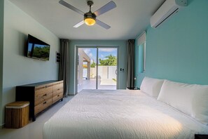 A bedroom with a bed, a ceiling fan, a TV, and a view of the outside. - Incredible 4BR with Private Pool near Eagle Beach (Noord)