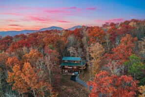 Un chalet entouré d’un feuillage automnal, sous un ciel dégagé.