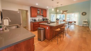 A modern kitchen with wooden cabinets, a stainless steel refrigerator, and a central island with stools.