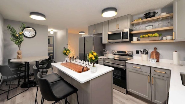 Une cuisine moderne avec des meubles gris, un îlot central, un four à micro-ondes et une cuisinière.