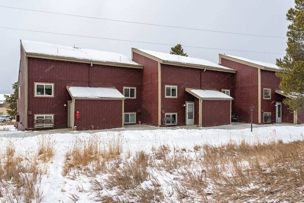 A multi-story building with a red exterior and snow-covered roof.