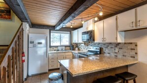 A kitchen with a granite countertop, stainless steel appliances, wooden beams, and a window. - Fraser 3BR Condo with Pool and Hot Tub (Fraser)