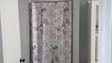 Ein Badezimmer mit einer Duschvorhang mit Pariser Motiven, einer weißen Tür und einem grauen Teppich auf dem Boden.