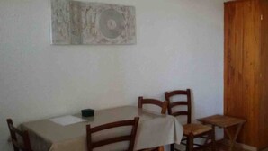 Een eethoek met een tafel, stoelen, een houten kast en een kunstwerk aan de wand.