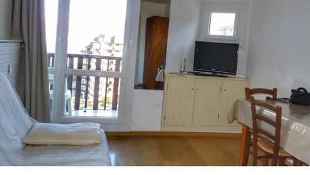 Een kamer met een bed, een tafel, een televisie en een raam.