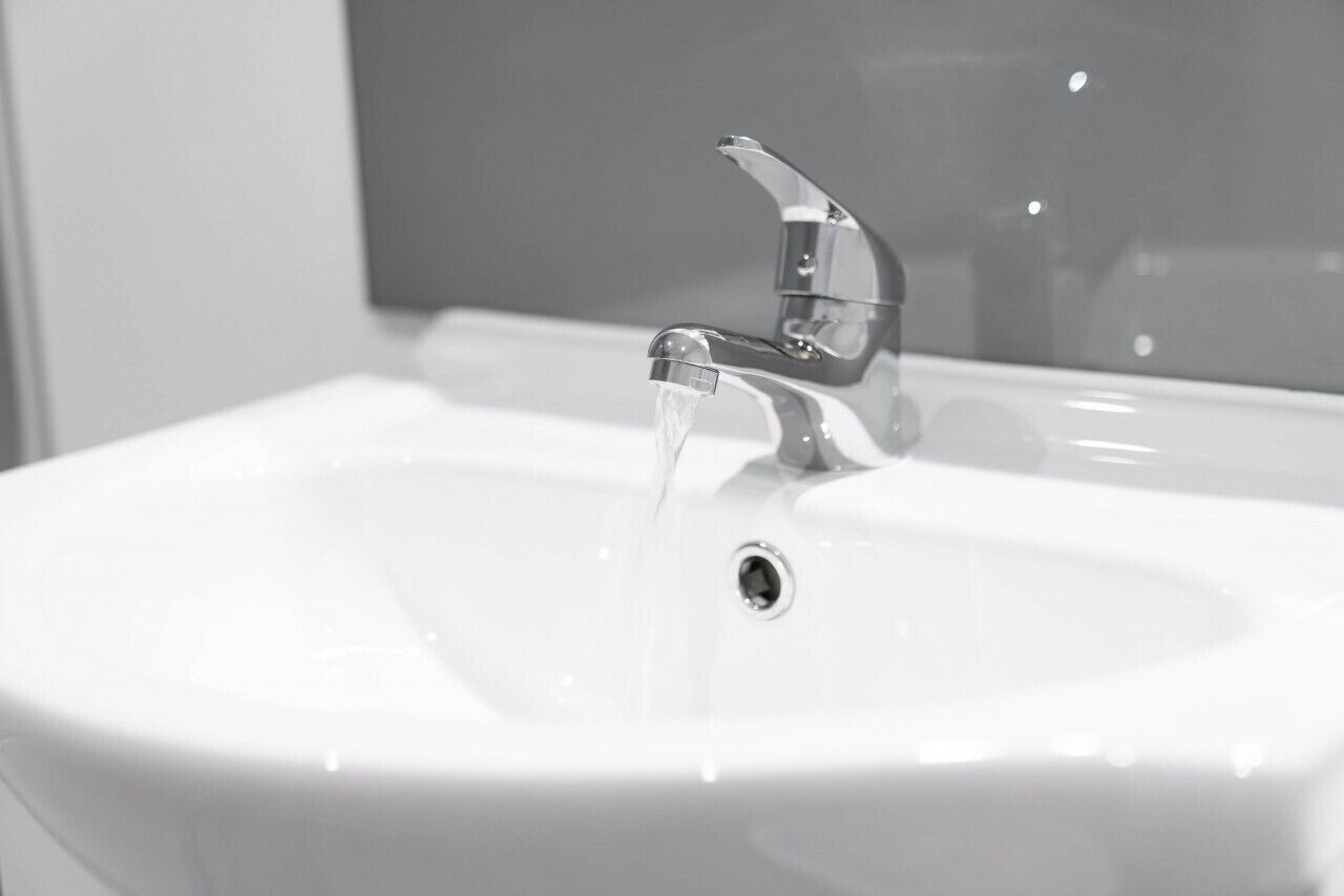 A white bathroom sink with a chrome faucet and a mirror above it.