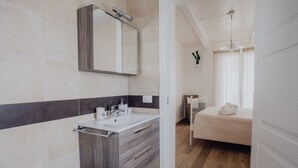 Un bagno moderno con un mobile vanitario in legno, uno specchio grande e un angolo toilette separato.